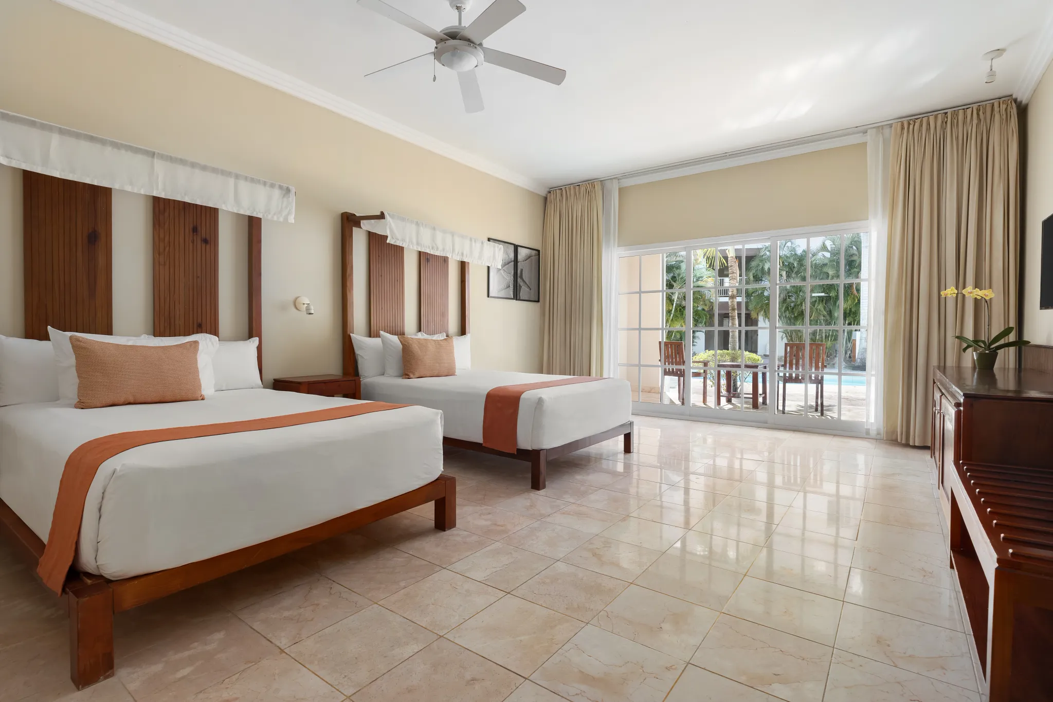 Deluxe Pool View room with two double beds and furnished terrace at Sunscape Coco Punta Cana overlooking the pool.
