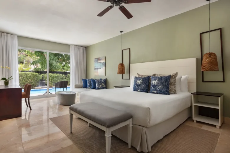 Luxury swim-out junior suite with king bed, tropical décor, and direct pool access at Sunscape Coco Punta Cana.