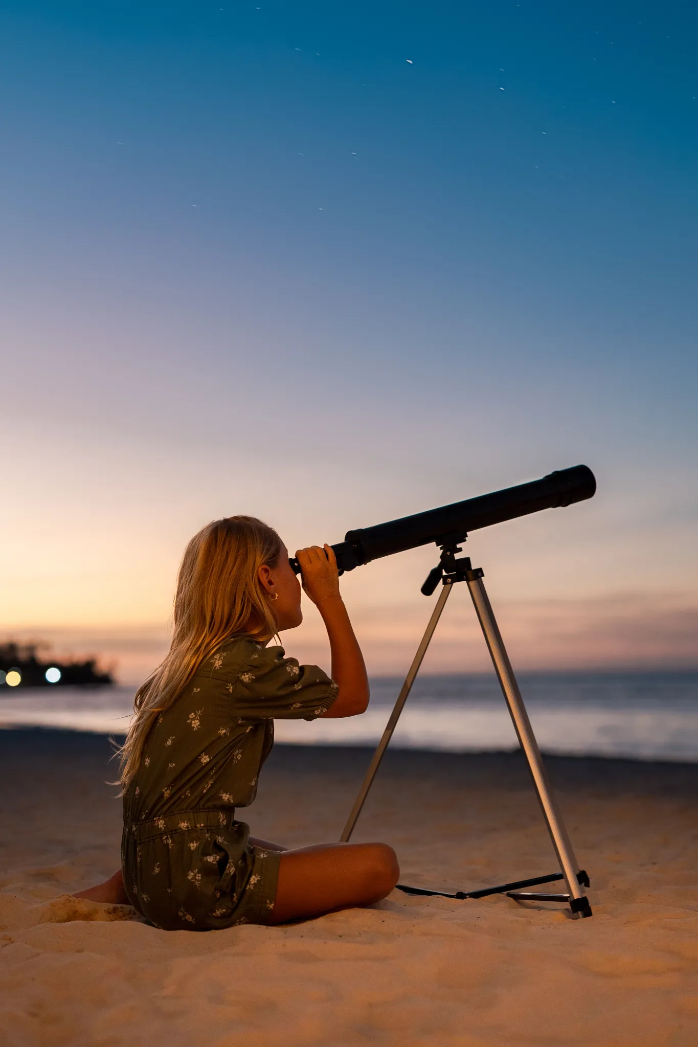 Child using a telescope for stargazing on the beach at sunset at Sunscape Coco Punta Cana Resort.