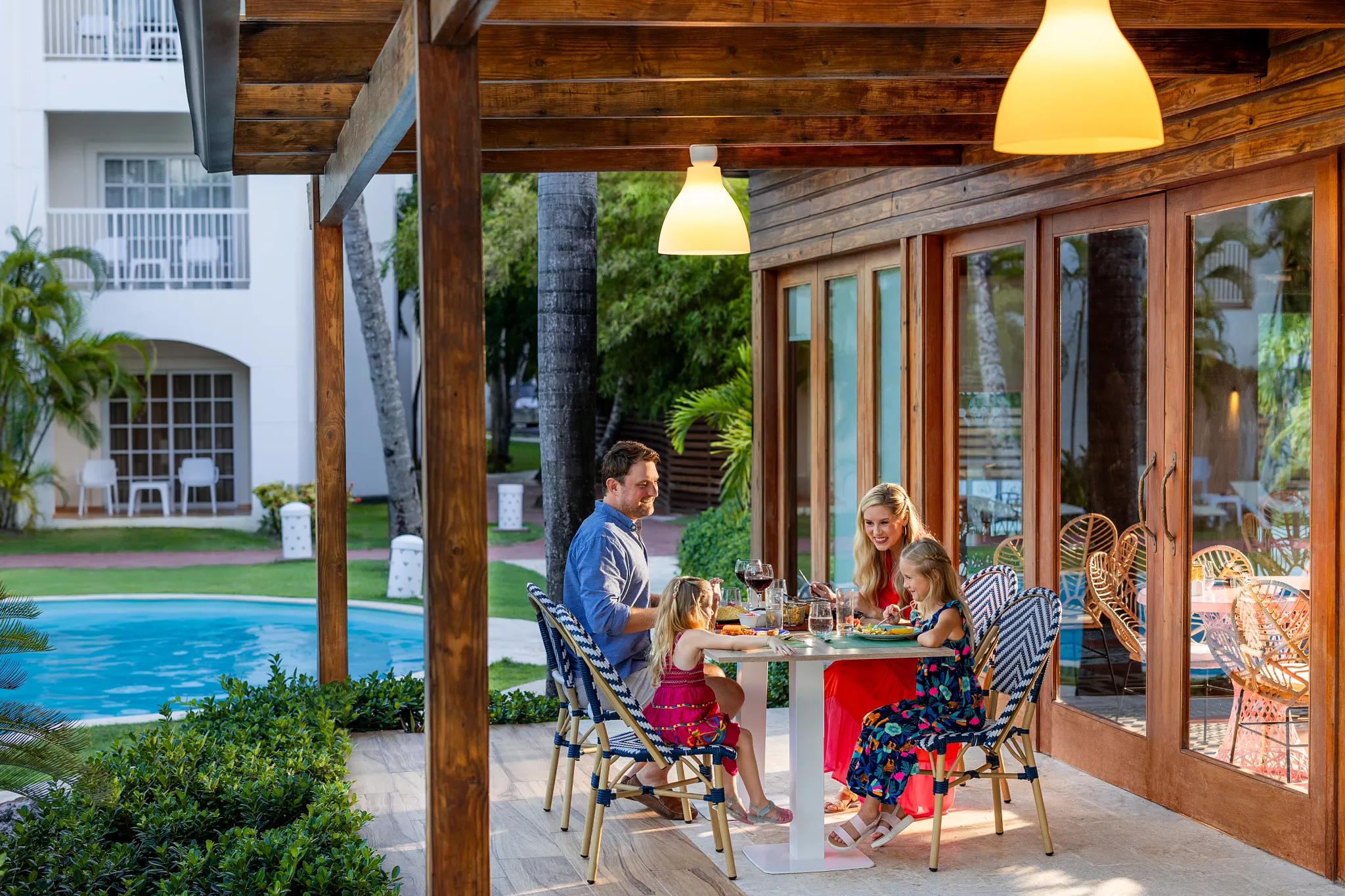 Family enjoying dinner together on an outdoor patio at Sunscape Coco Punta Cana Resort.