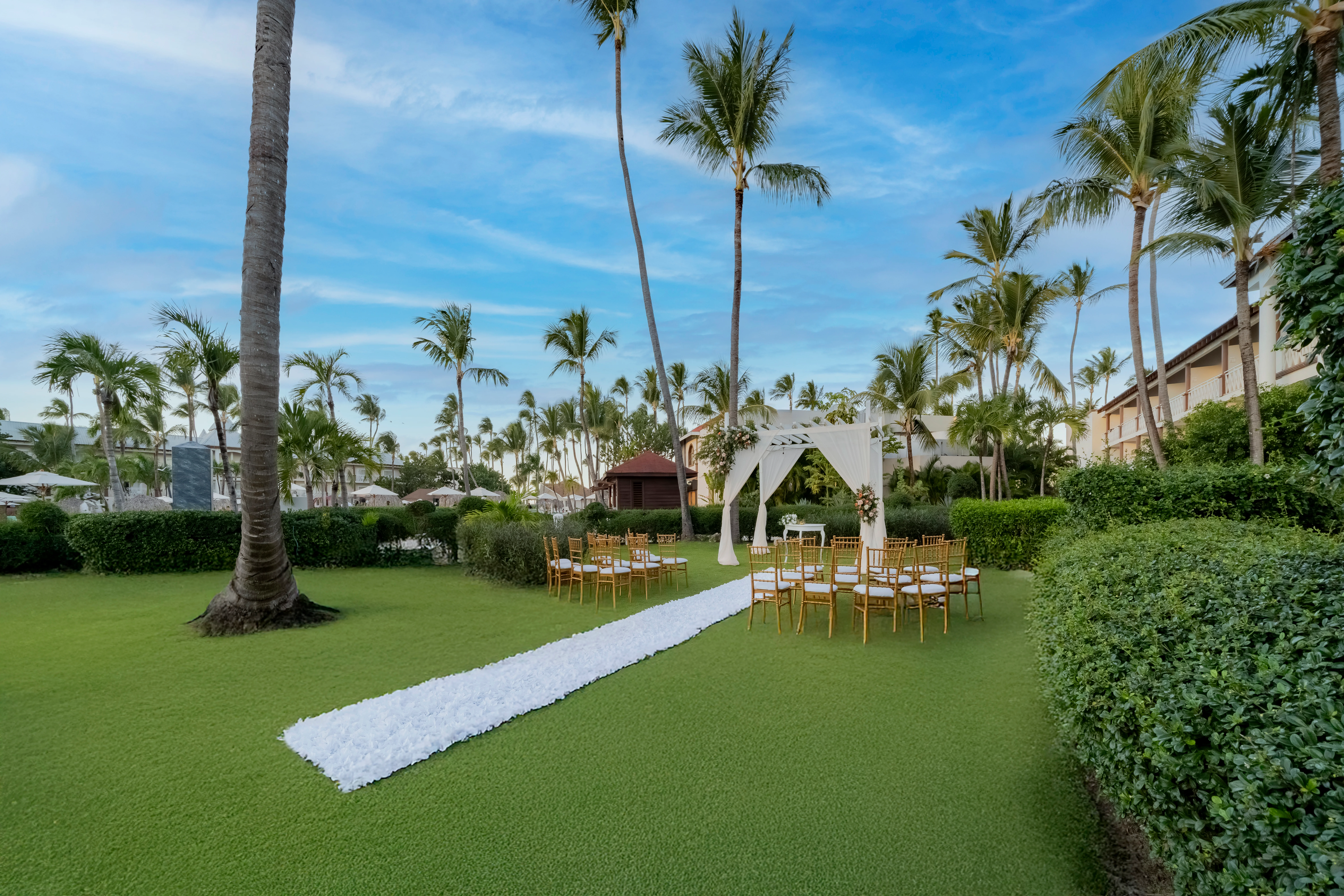 Elegant garden wedding ceremony setup surrounded by palm trees at Sunscape Coco Punta Cana Resort.
