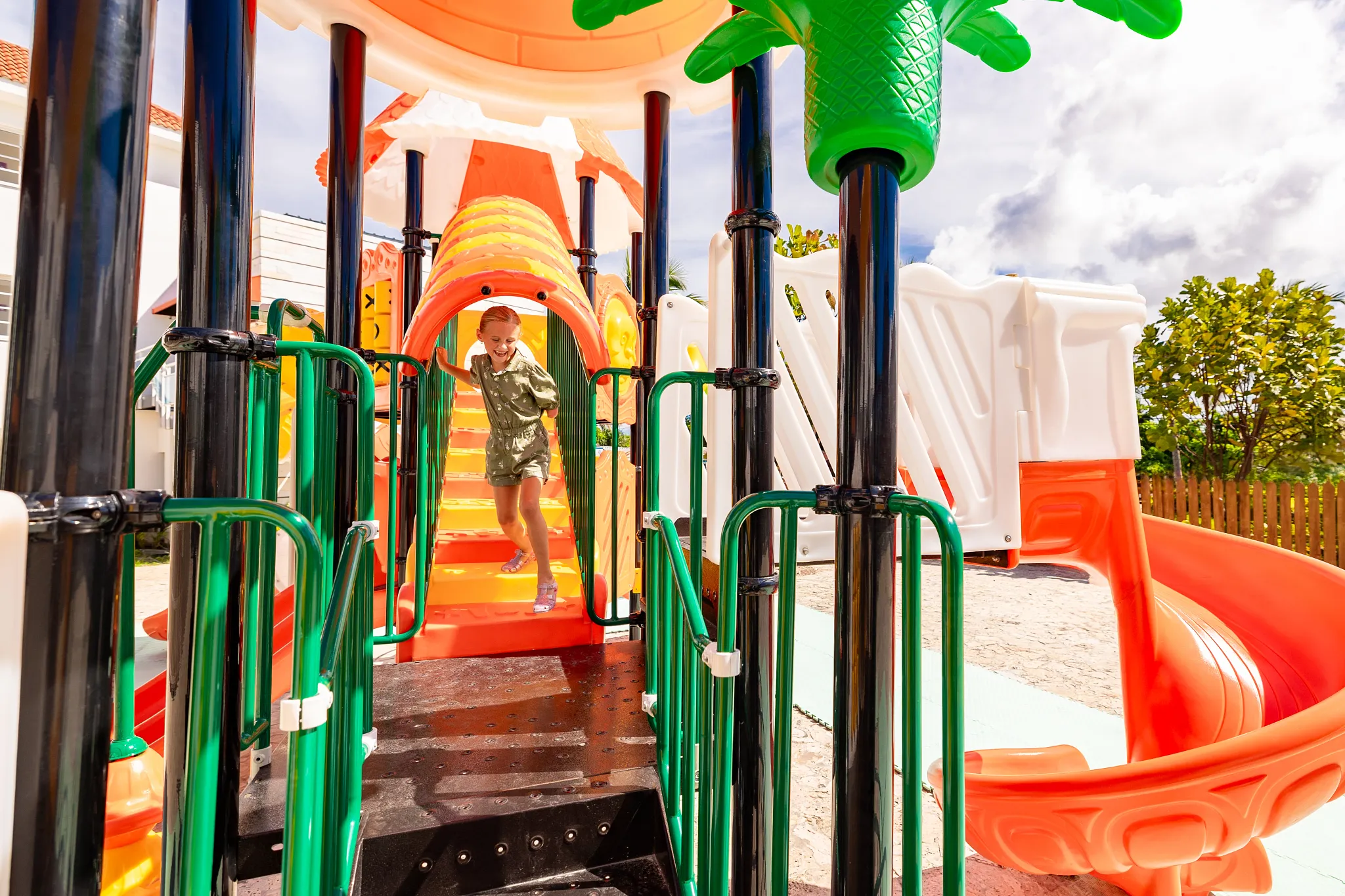 Young child playing on a colorful outdoor playground at Sunscape Coco Punta Cana Resort.