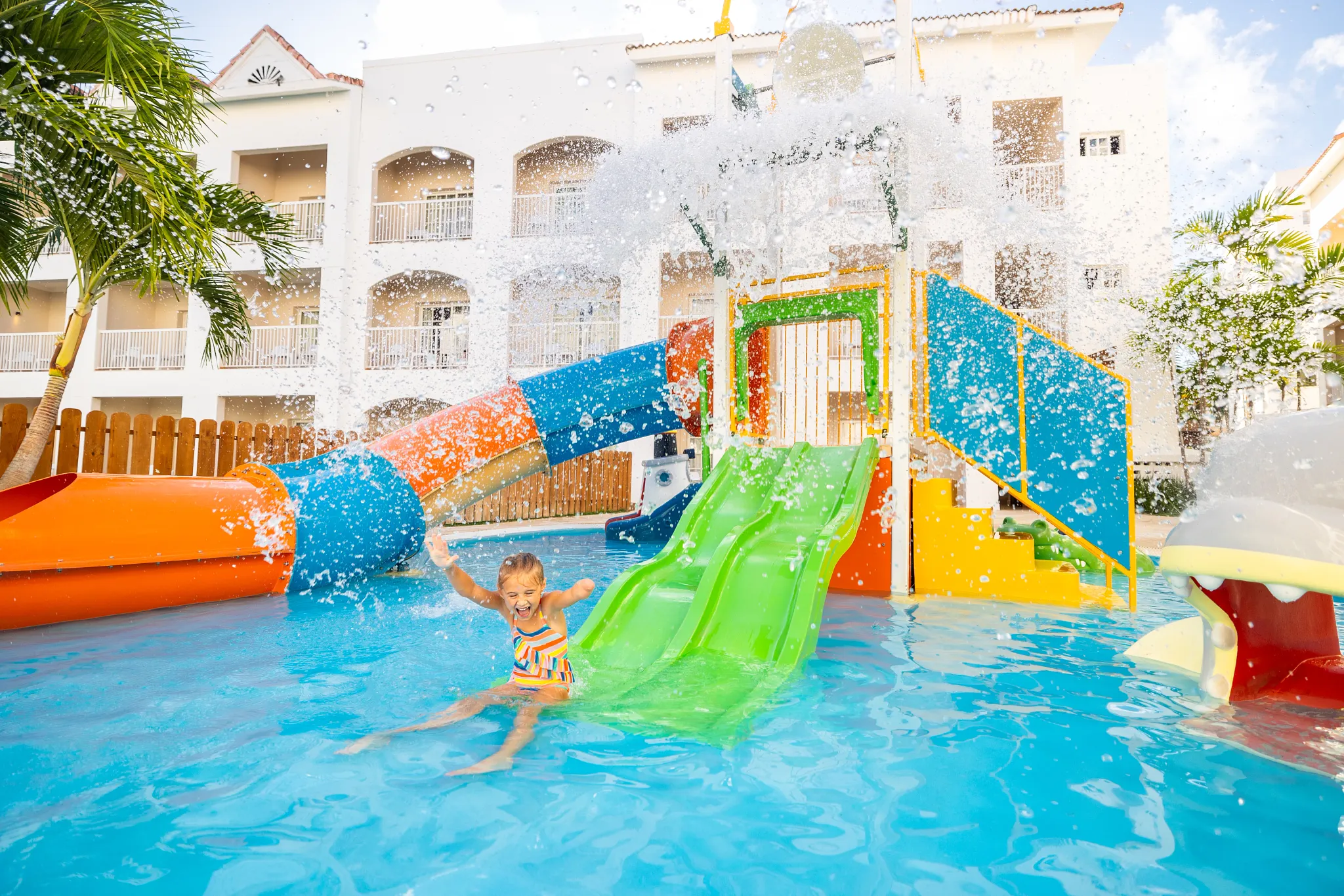Child playing on colorful water slides and splash features at Sunscape Coco Punta Cana Resort.