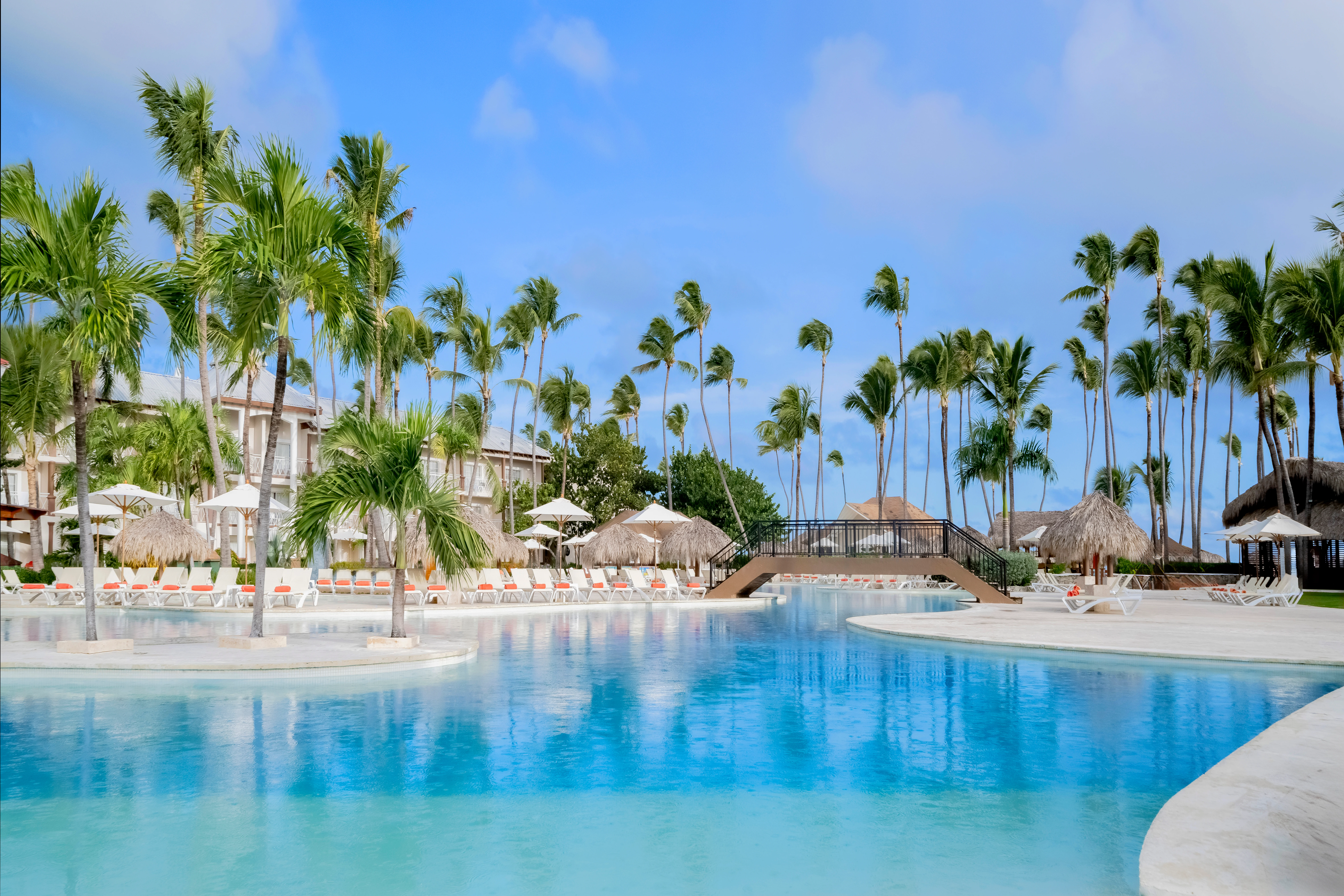 Large tropical swimming pool surrounded by palm trees at Sunscape Coco Punta Cana Resort.