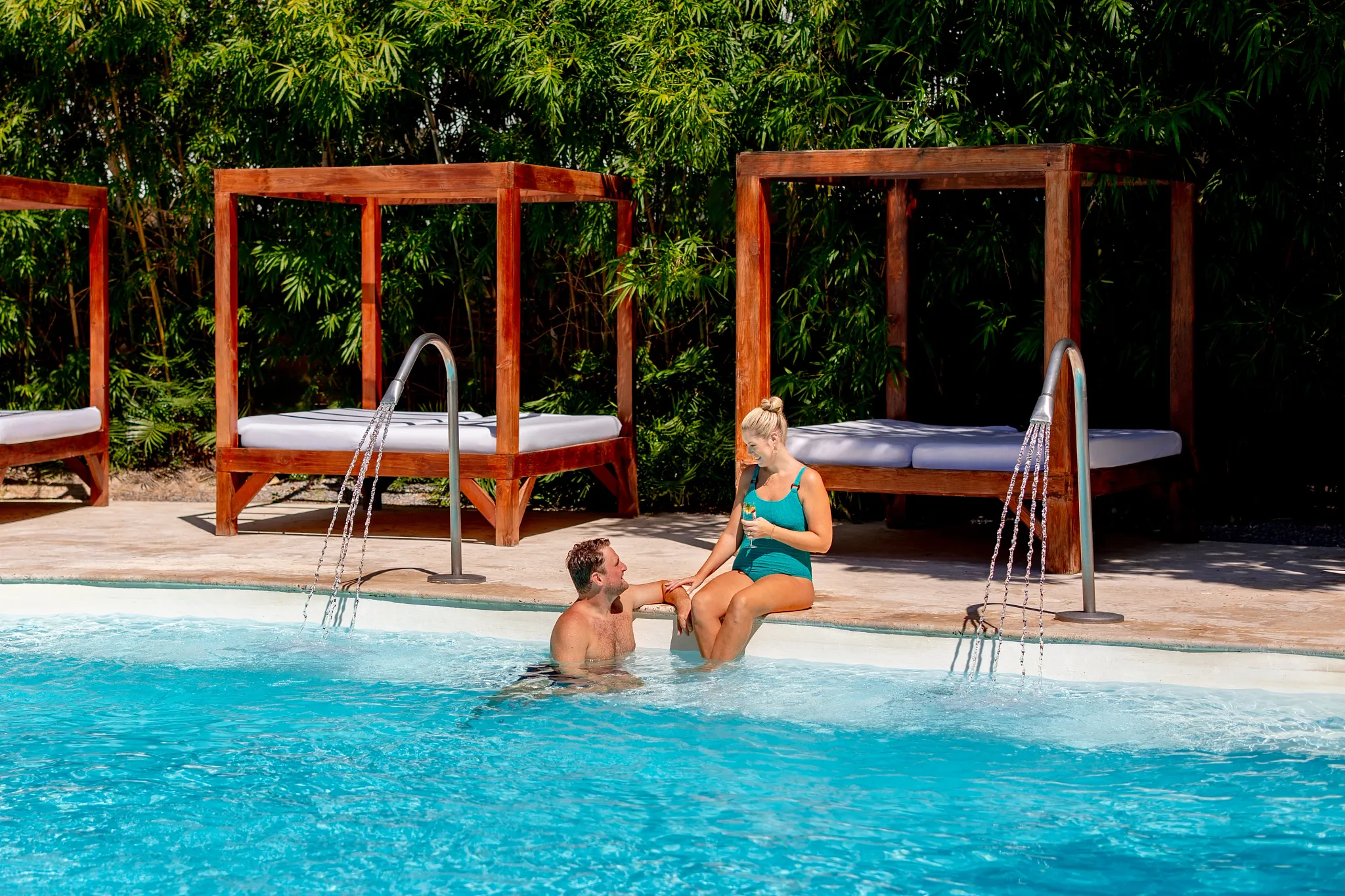 Couple relaxing by the resort pool with luxury cabanas at Sunscape Coco Punta Cana.