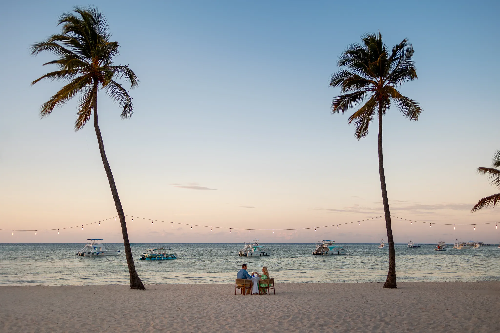 Couple enjoying a romantic beachfront dinner at sunset at Sunscape Coco Punta Cana Resort.