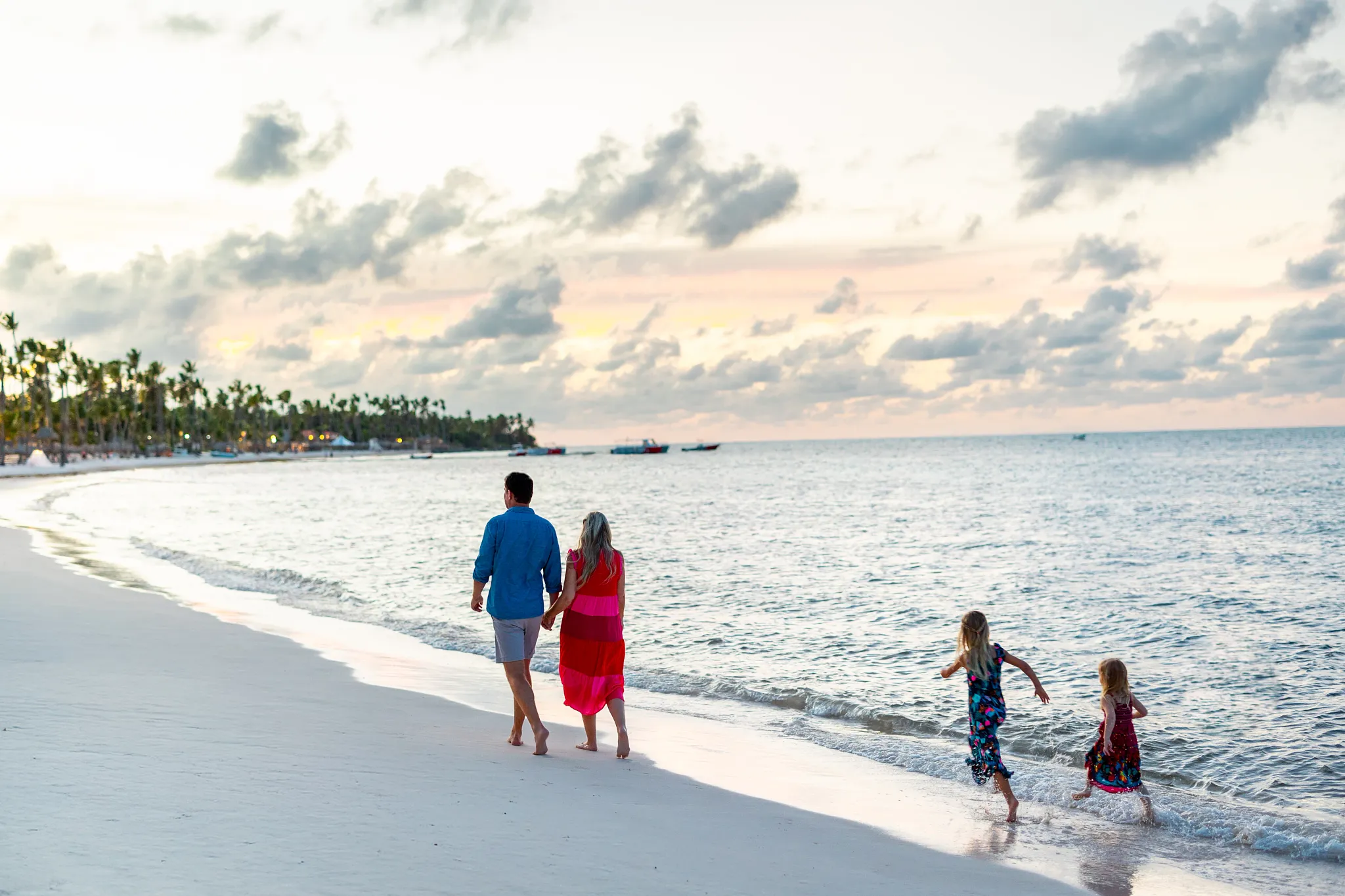 Family walking along the beach at sunset at Sunscape Coco Punta Cana Resort.