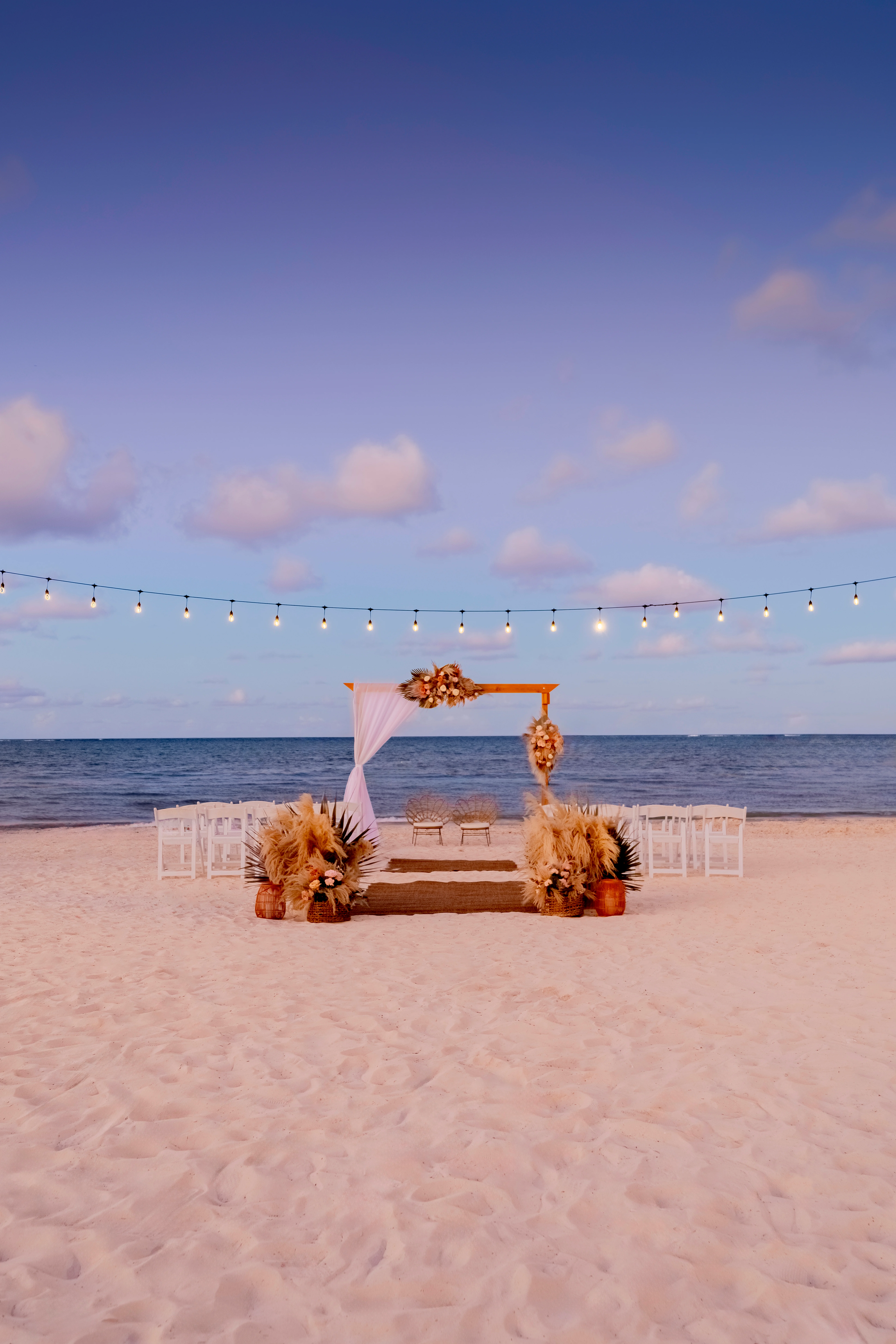 Romantic sunset beach wedding ceremony with string lights at Sunscape Coco Punta Cana Resort.
